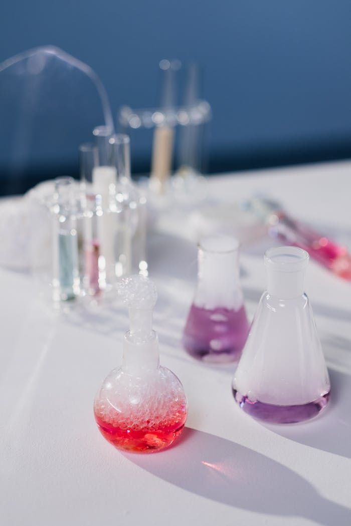Colorful chemical reactions in laboratory flasks on a white surface with natural light.